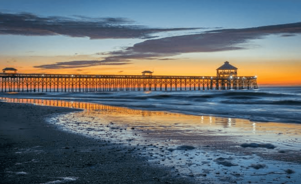 Charleston beach pier at sunset with ocean waves and colorful evening sky 