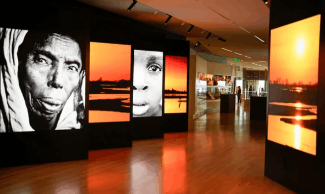 Interactive digital display panels showcasing portraits and landscapes inside the International African American Museum in Charleston, South Carolina.