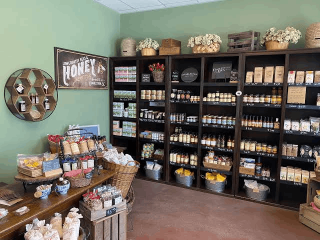 Wooden display shelves and baskets filled with jars of local honey, artisanal foods, and Lowcountry treats inside a Charleston specialty souvenir boutique.